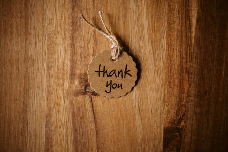 Thank you word written in a card on wooden background with selective focus. Love and gratitude concept.の写真素材