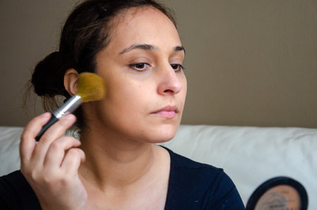 A closeup shot of a female putting on makeup with a brushの写真素材