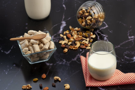 A closeup of a quick breakfast consisting of milk, nuts and cookies on a marble counterの写真素材