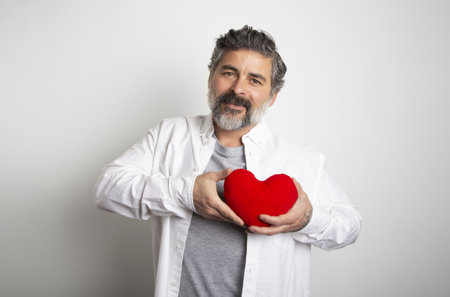 A bearded male holding a red heart on a white background. Happy happy Dayの写真素材