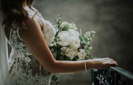 A bride wearing the beautiful white wedding dress and a shiny bracelet holding a bridal bouquetの写真素材