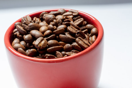 A closeup shot of roasted coffee beans in a red bowl