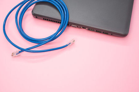 A high angle shot of a LAN cable on a laptop against a pink backgroundの写真素材