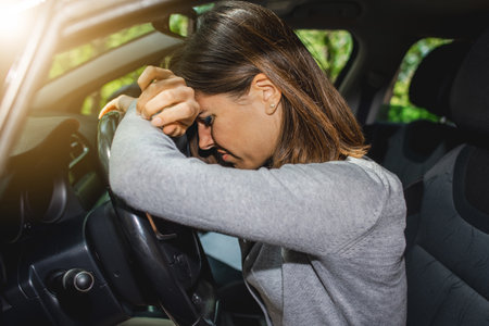 A Caucasian female driver having a headache during driving