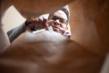 A Hispanic man is opening a parcel delivered at home due to pandemic