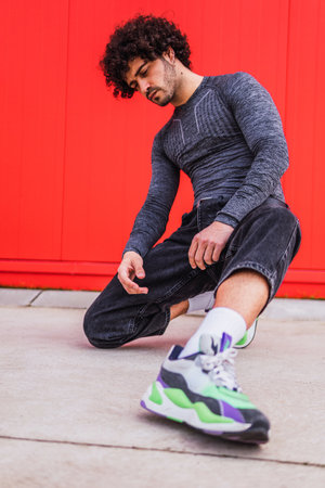 A vertical shot of a Caucasian young athlete posing in front of a red wallの写真素材
