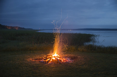 A beautiful shot of a bonfire with flying flames near the waterの写真素材