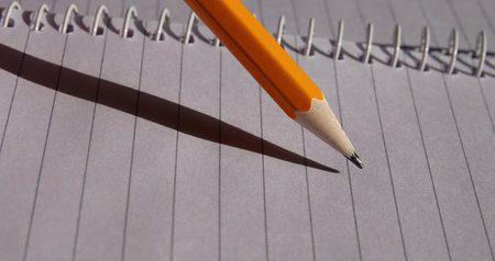 A closeup of a pencil hovering over an empty notebook page, preparing to writeの写真素材
