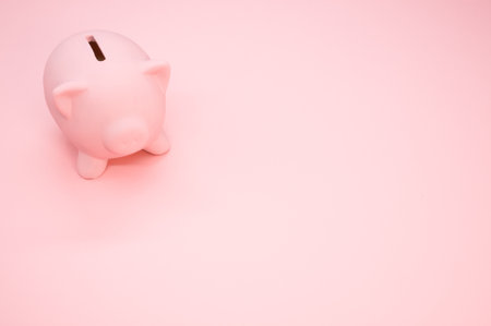 A closeup of a piggy bank on a pink background with space for your text - savings and banking conceptの写真素材