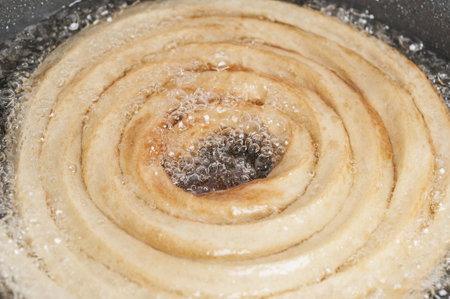 A high angle shot of a homemade churro being fried in oil