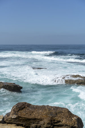 A vertical shot of the blue sea and a rocky shoreの写真素材