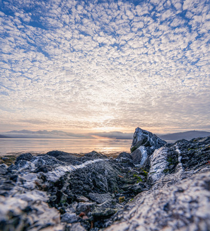A stunning view of a rocky coast during sunset with cirrocumulus cloud in the blue sky in Senjaの写真素材