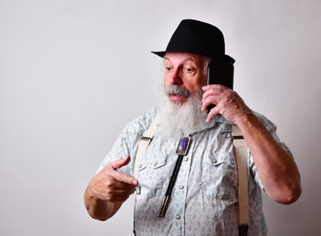 A senior Caucasian bearded male having a serious talk on his mobile phoneの写真素材
