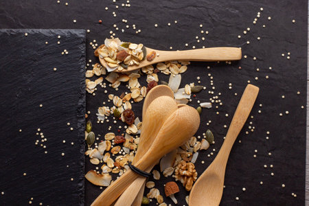 A healthy and delicious muesli with wooden spoons on a black background