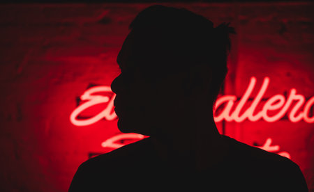 A Hispanic male on a wall background with red neon lightsの写真素材