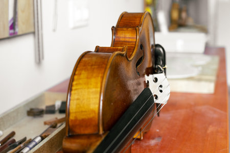 A broken violin set on a dusty wooden table in the luthier's workshop waiting for repairの写真素材