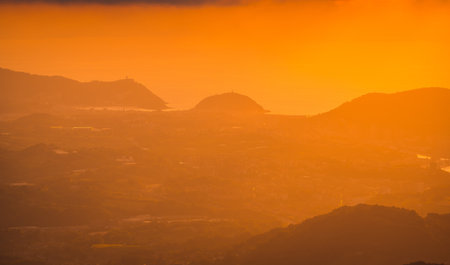 An aerial shot of gradient of orange colors in a beautiful sunset from a top of a mountainの写真素材