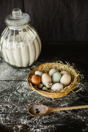 A vertical shot of fresh chicken and quail eggs in a basket on a kitchen table