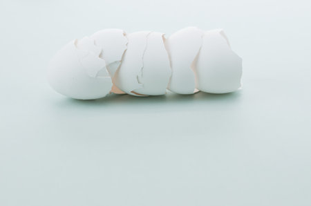 A closeup of a stack of cracked eggshells on a gray surface under the lightsの写真素材