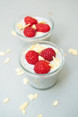 chia pudding decorated with fresh raspberries, almonds and mint leaves, served in a small glass bowlの写真素材