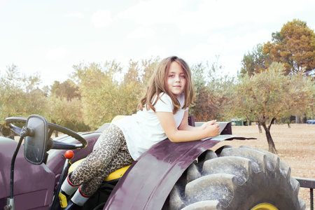 A shallow focus of a Spanish kid on a farm tractor in a field under the sunlight in Spainの写真素材