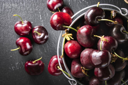 A top view of sweet cherries in a bucket and on a tableの写真素材