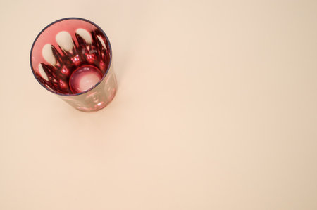A closeup shot of a red glass isolated on a pink surface with space for textの写真素材