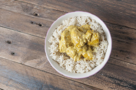 A top view of chicken curry and rice in a bowl on a wooden tableの写真素材