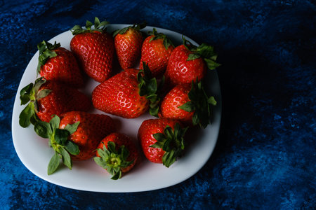 A closeup shot of delicious strawberries served on a white plateの写真素材