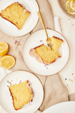 A vertical shot of a delicious citron cake with glaze and flower on top on a white tableの写真素材
