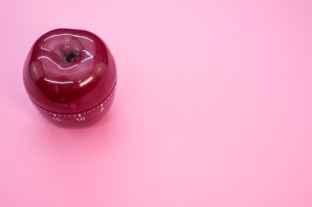 An apple-shaped kitchen timer isolated on pink backgroundの写真素材