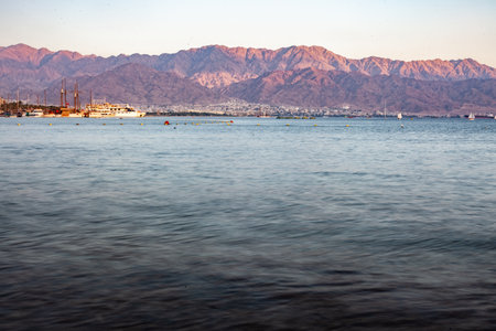 A beautiful shot of a lake with mountains and cliffs on a distant shoreの写真素材