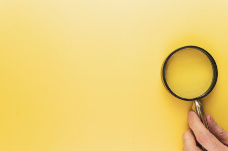 A person holding a magnifier isolated on a yellow backgroundの写真素材