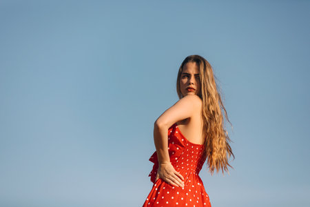 A young attractive Caucasian female posing outdoors in a red dressの写真素材