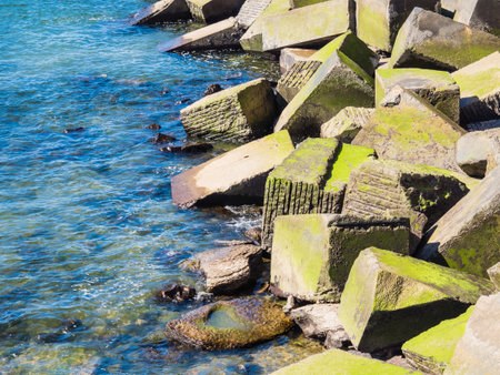 A closeup of the giant dirty rocks covered in moss in the Urumea riverの写真素材