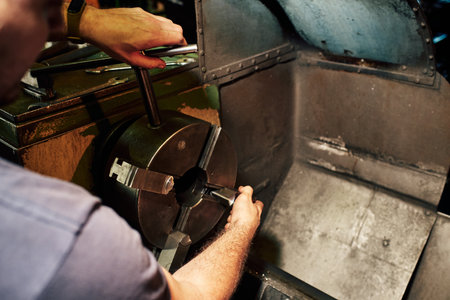A closeup shot of a Hispanic mechanical engineer controlling the lathe machine in a factoryの写真素材