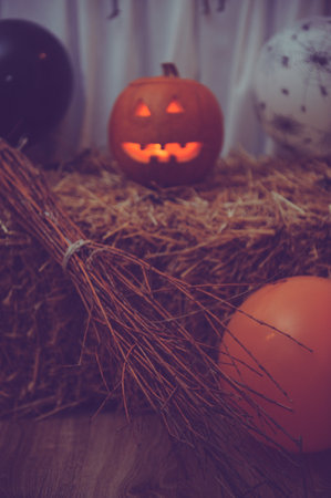 A vertical shot of a broom and a carved pumpkin for Halloween decorationsの写真素材