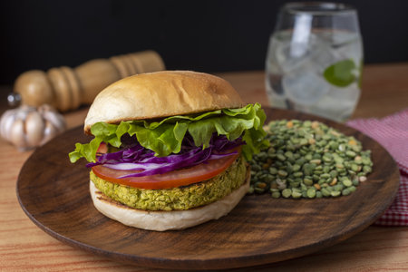 A closeup of a plate of burger with peas on a wooden tableの写真素材