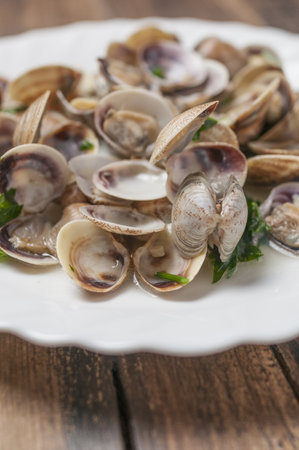 A selective focus shot of clams in wine sauce on a white plateの写真素材