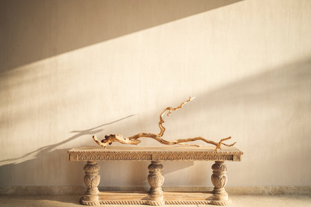 A driftwood branch sculpture on a carved console table by the beige wallの写真素材
