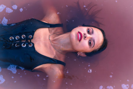 A young brunette female lying in the water looking at the camera Alicante, Spain
