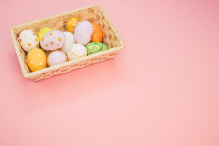 Decorated eggs in woven basket isolated on pink backgroundの写真素材
