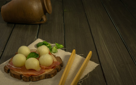 juicy melon with ham typical summer food on dark backgroundの写真素材