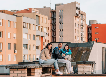 Young people sitting on rooftop of residential building in cityの写真素材