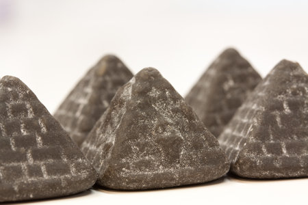 A closeup shot of tasty pyramid liquorice candies on a white blurred backgrouの写真素材