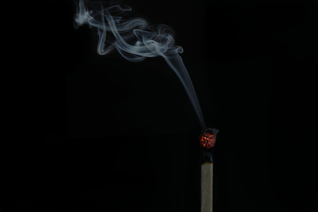 A burning match isolated on a black backgroundの写真素材
