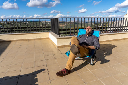 Stock photo of man resting and lying in a chair while enjoying sunny day.の写真素材