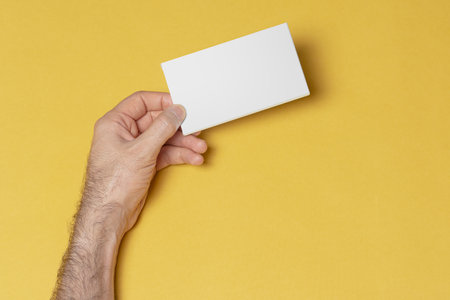 A closeup shot of a male left hand holding a pillbox in front of yellowの写真素材
