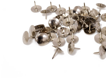 A closeup shot of many metal push pins on a white background