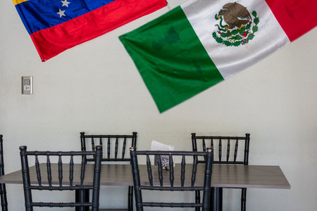 A restaurant with tables for dinners with the flags of Mexico and Venezuela - multiethnic cafe, latin american foodの写真素材
